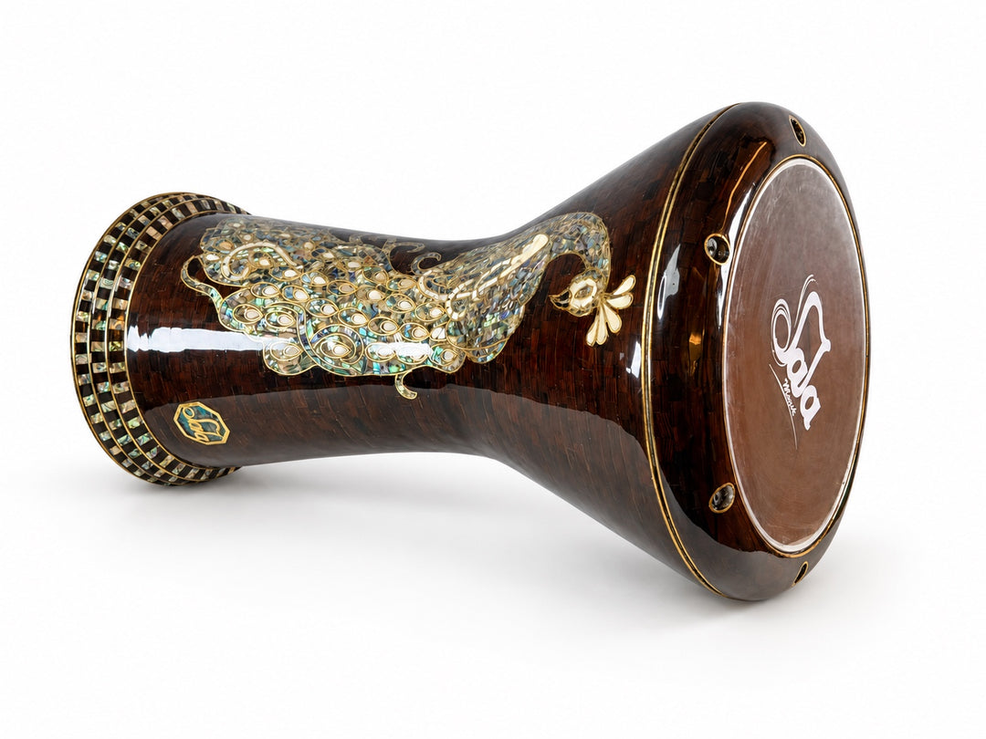 Sala Amber Peacock Sombaty darbuka on its side, showing the Sala-branded drumhead and a pale peacock motif on a dark amber-brown mosaic background.